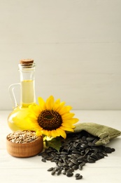 Photo of Composition with sunflower oil on white wooden table, space for text