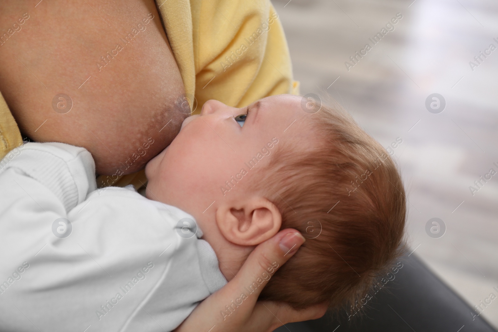 Photo of Young woman breast feeding her little baby at home, closeup