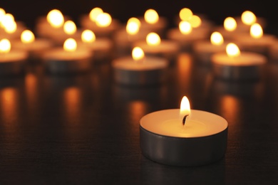 Burning candles on wooden table, space for text. Symbol of sorrow