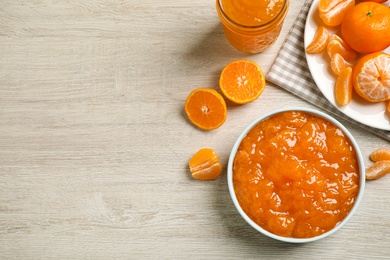 Photo of Flat lay composition with delicious tangerine jam on wooden table. Space for text