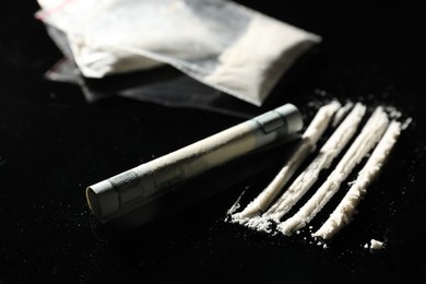 Photo of Drug addiction. Cocaine and rolled dollar banknote on black table, closeup