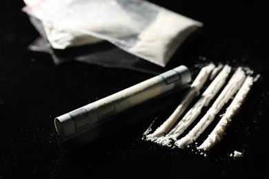 Drug addiction. Cocaine and rolled dollar banknote on black table, closeup