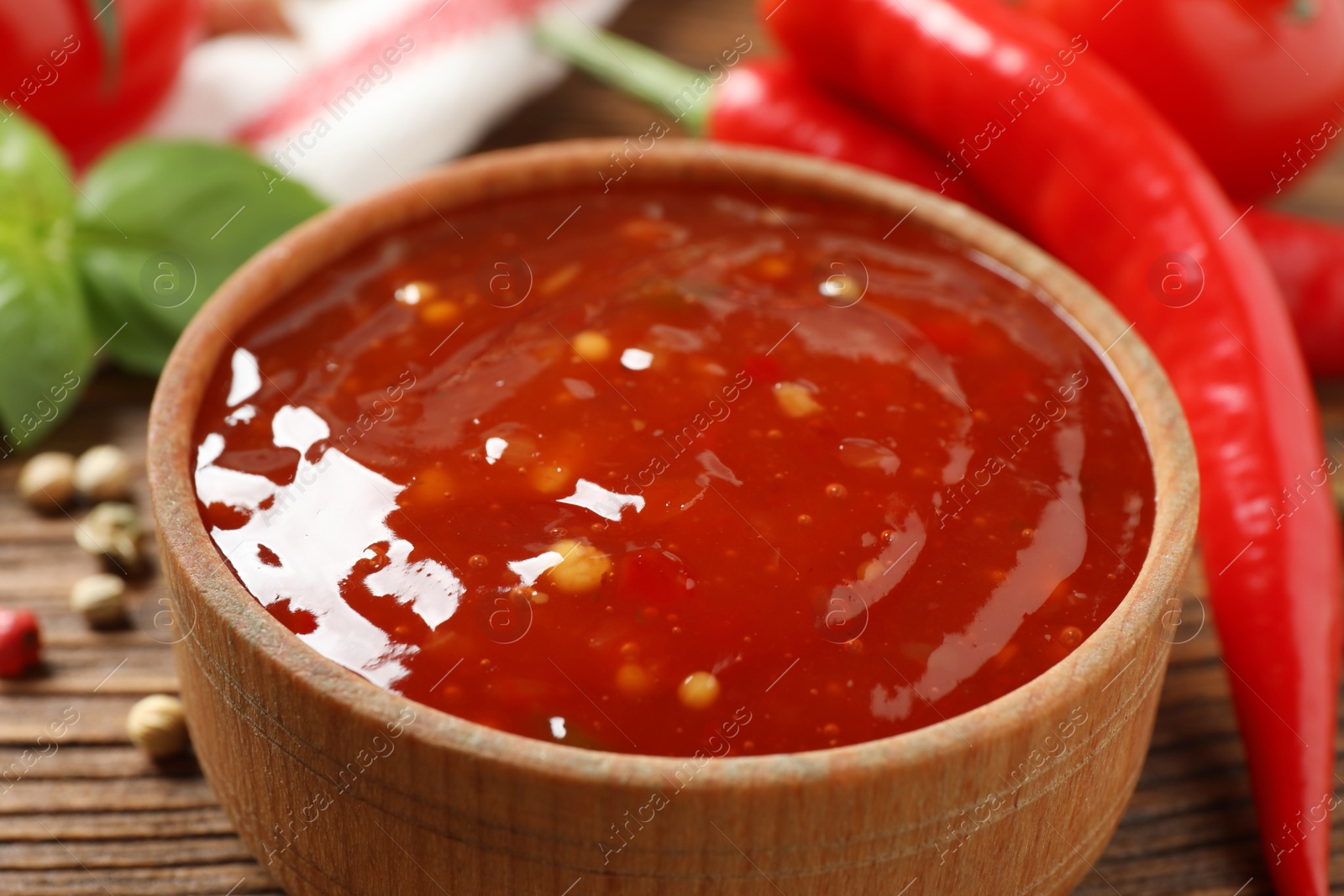 Photo of Spicy chili sauce in bowl on wooden table, closeup