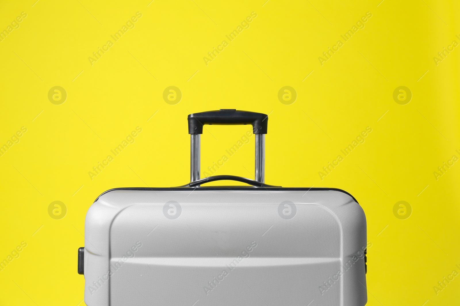 Photo of Stylish grey suitcase with handle on yellow background
