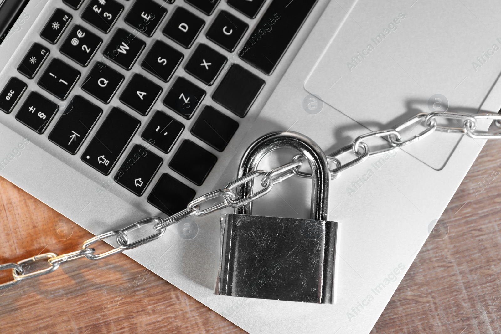 Photo of Cyber security. Laptop with padlock and chain on wooden table, top view