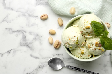 Photo of Tasty pistachio ice cream served on white marble table, flat lay. Space for text