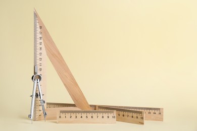 Photo of Different rulers and compass on light yellow background