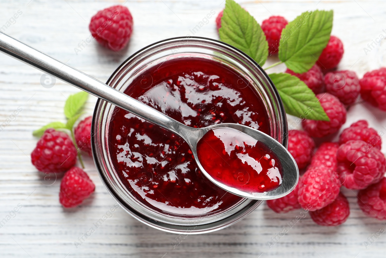 Image of Sweet raspberry jam and fresh berries on white wooden table, flat lay