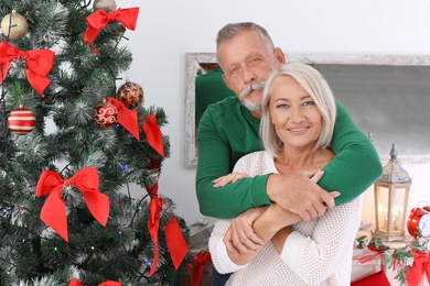 Mature couple near Christmas tree at home