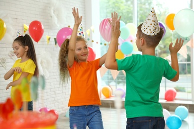 Photo of Happy children playing at birthday party in decorated room