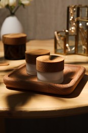 Jars of cream and tray on wooden table