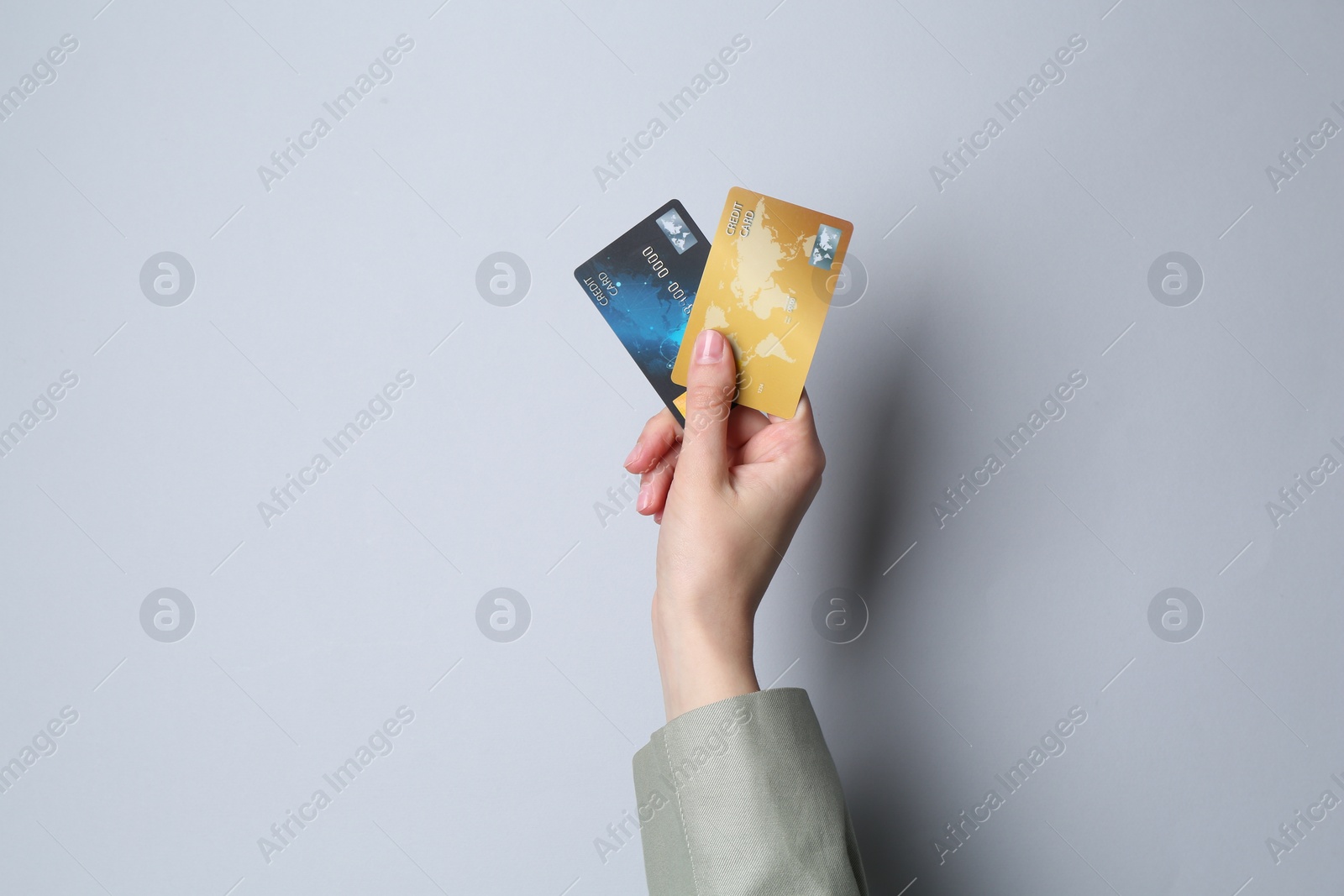 Photo of Woman holding credit cards on light grey background, closeup