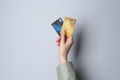 Woman holding credit cards on light grey background, closeup