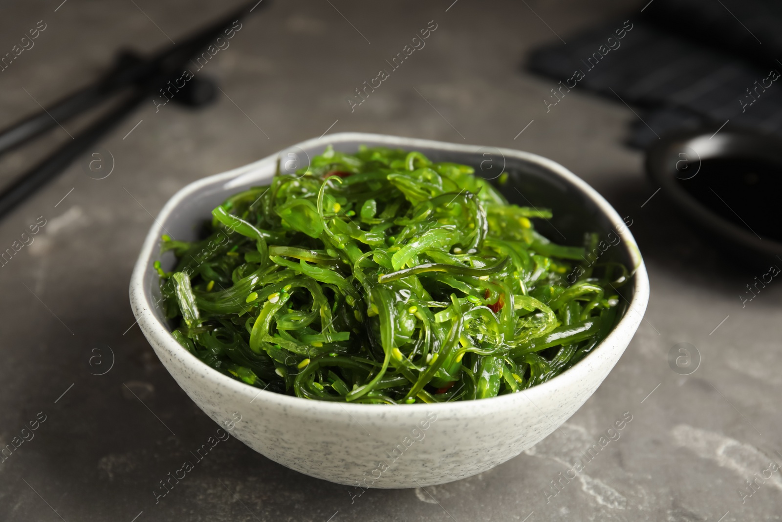 Photo of Japanese seaweed salad served on grey table, closeup