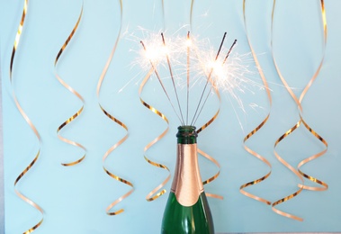 Photo of Creative composition with bottle of champagne and sparklers on color background