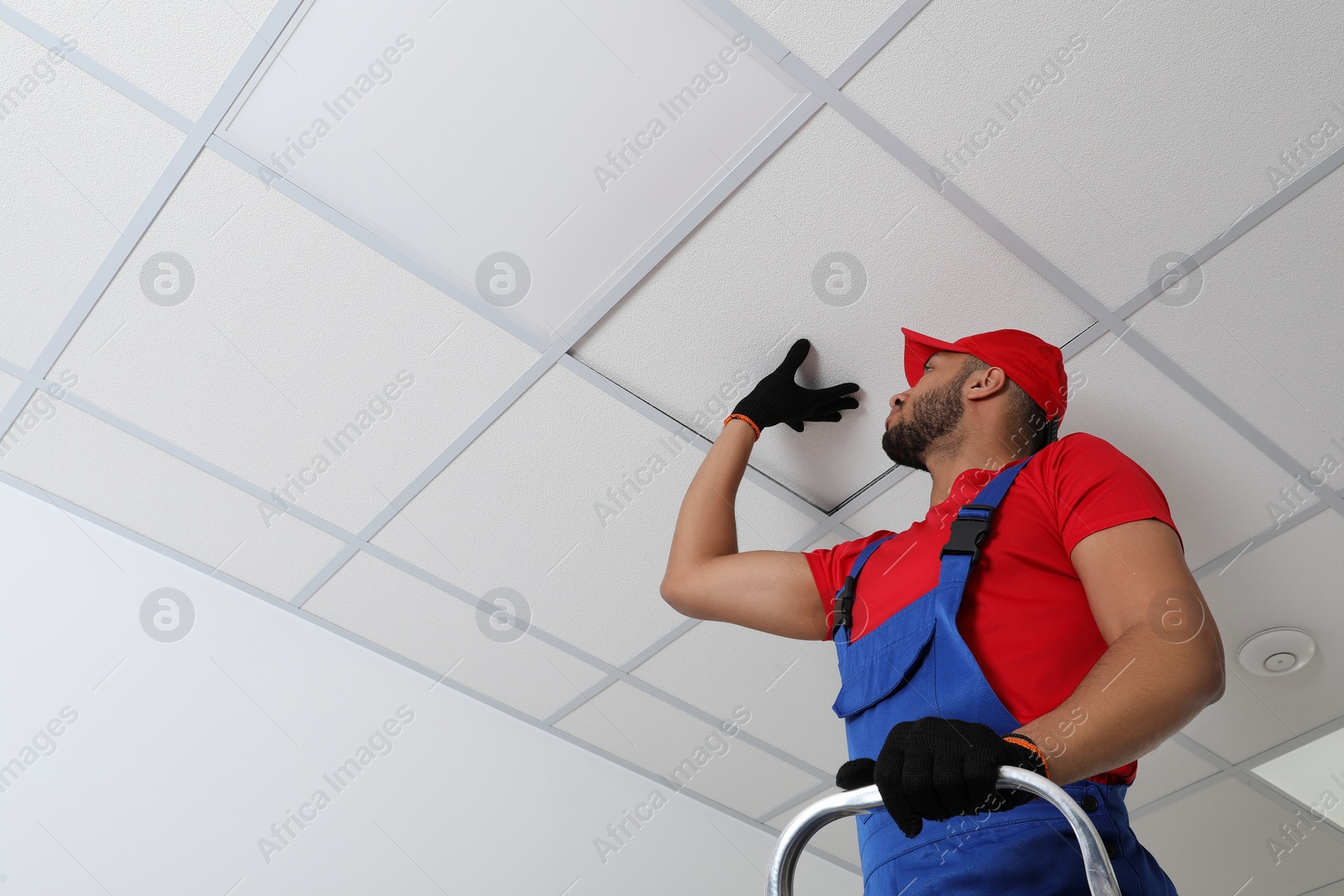 Photo of Electrician repairing ceiling light indoors, low angle view. Space for text