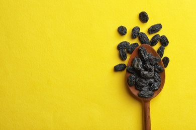 Photo of Spoon with raisins and space for text on color background, top view. Dried fruit as healthy snack