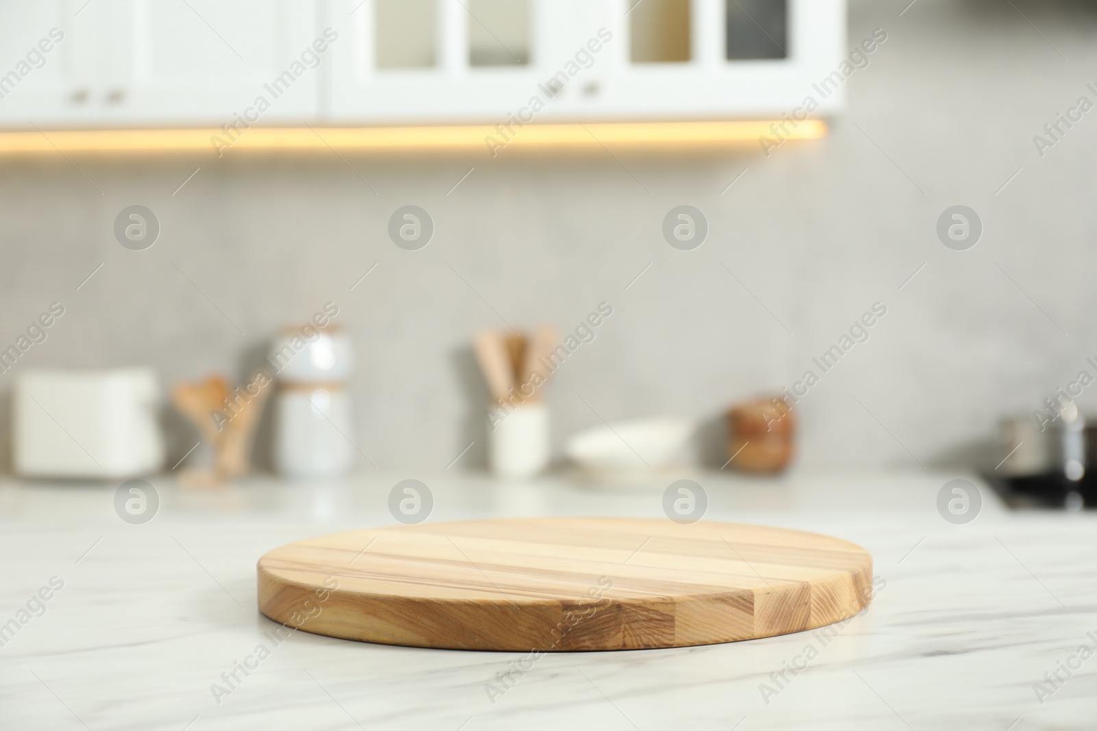Photo of Wooden cutting board on white marble table in kitchen. Space for text