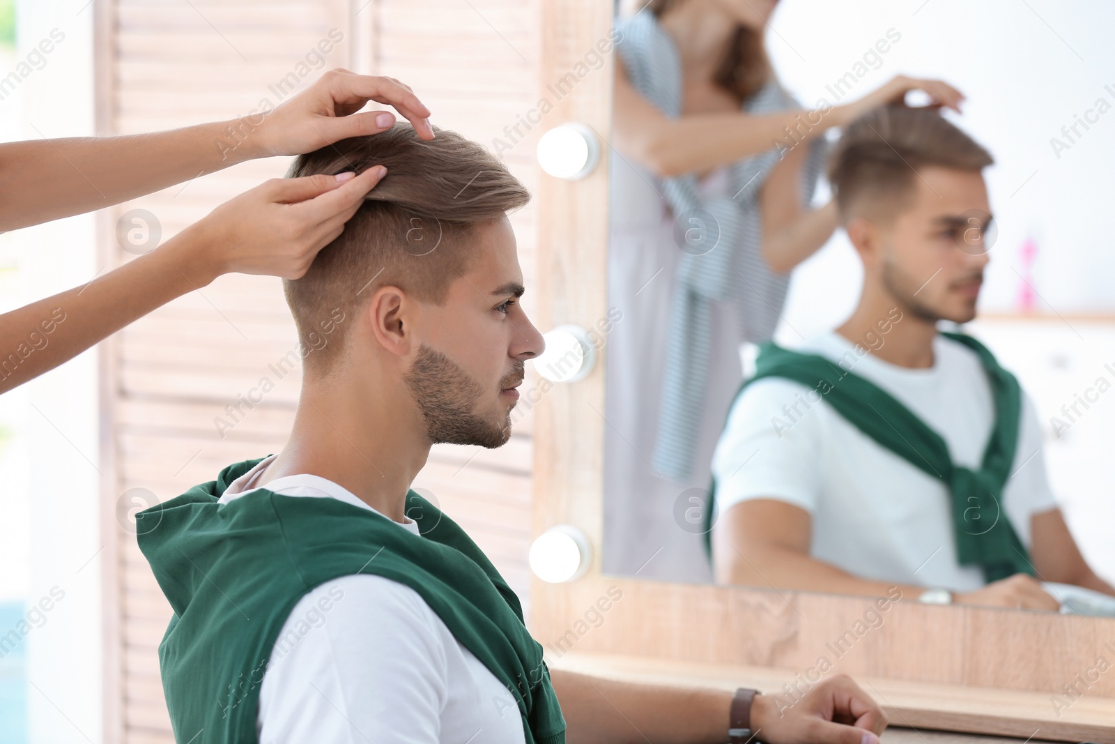 Photo of Professional hairdresser working with young man in barbershop. Trendy hair color