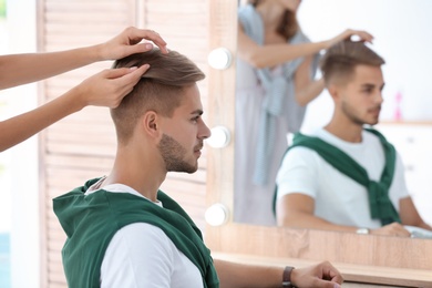 Photo of Professional hairdresser working with young man in barbershop. Trendy hair color