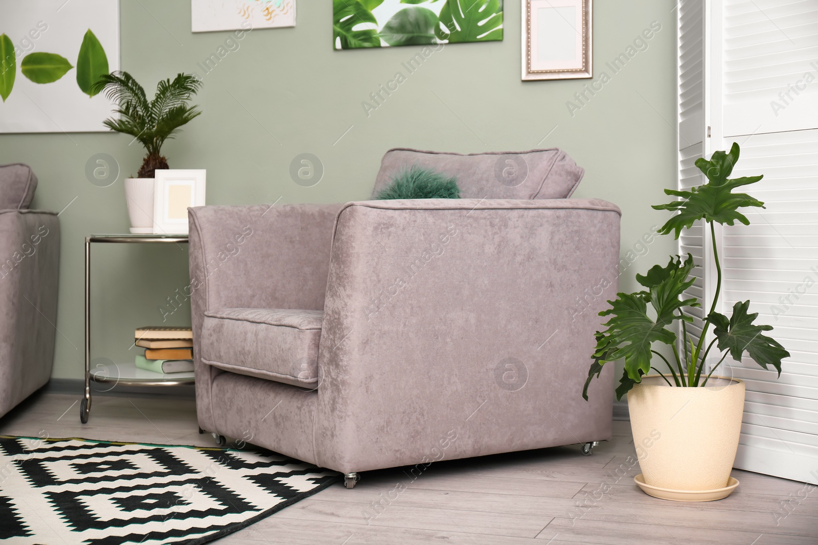 Photo of Tropical plants with green leaves and comfortable armchair in room interior