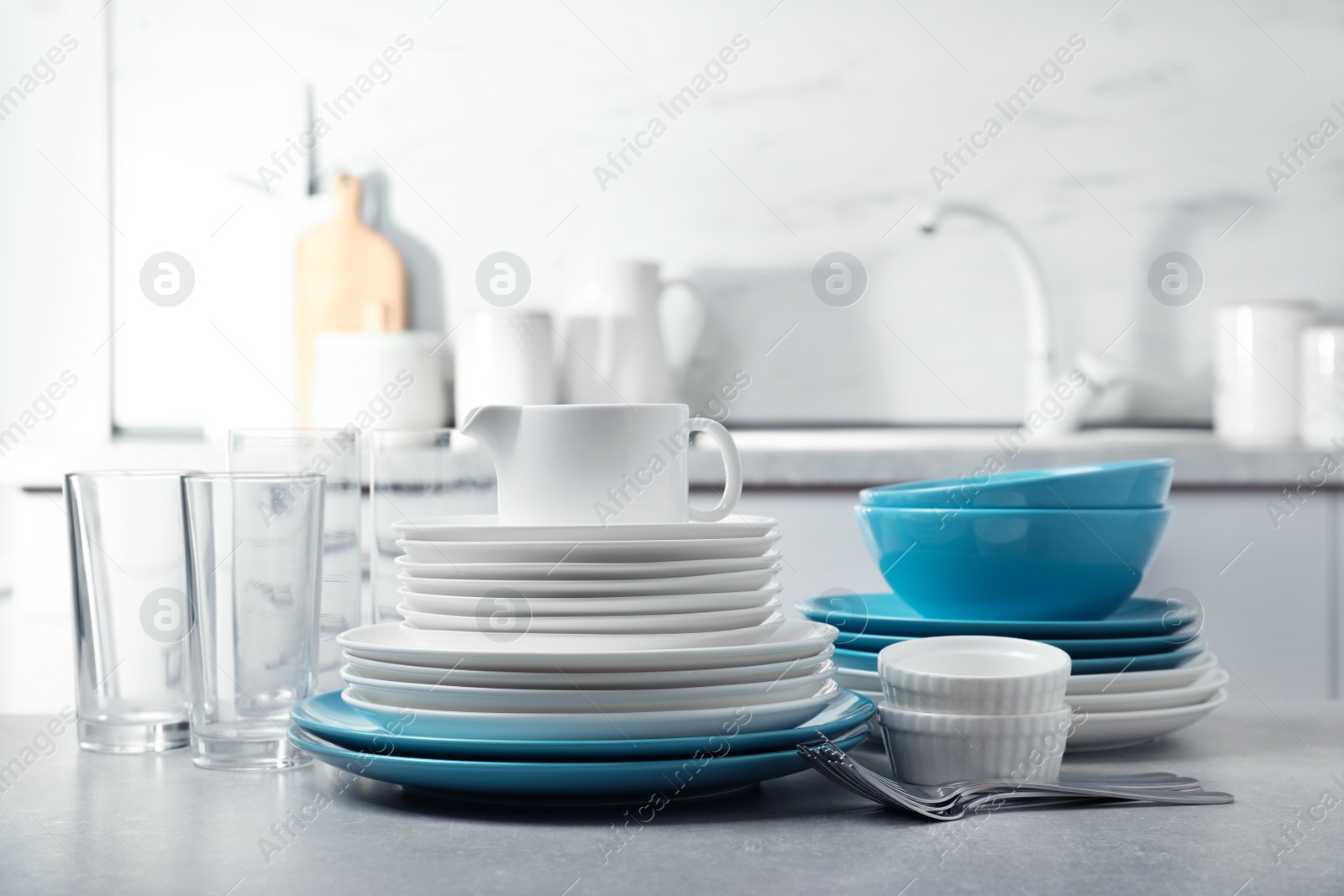 Photo of Set of clean dishes and cutlery on table in kitchen