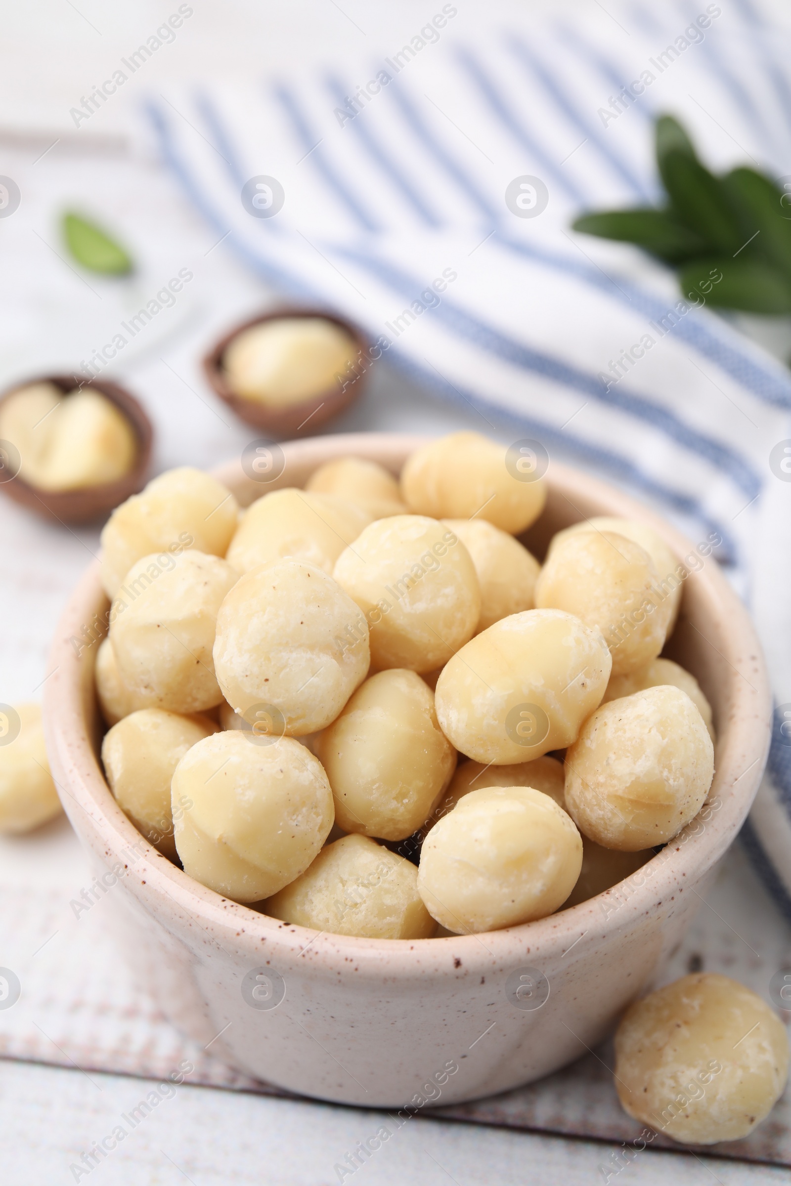 Photo of Tasty peeled Macadamia nuts in bowl on light table