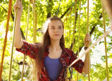 Teenage girl climbing in adventure park. Summer camp