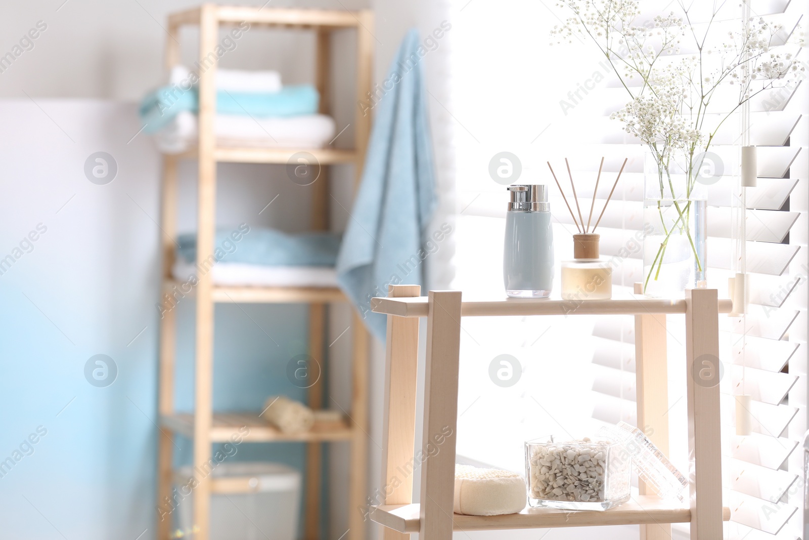 Photo of Soap dispenser, reed air freshener and flowers on wooden stand in bathroom. Space for text