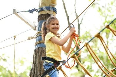 Little girl climbing in adventure park. Summer camp