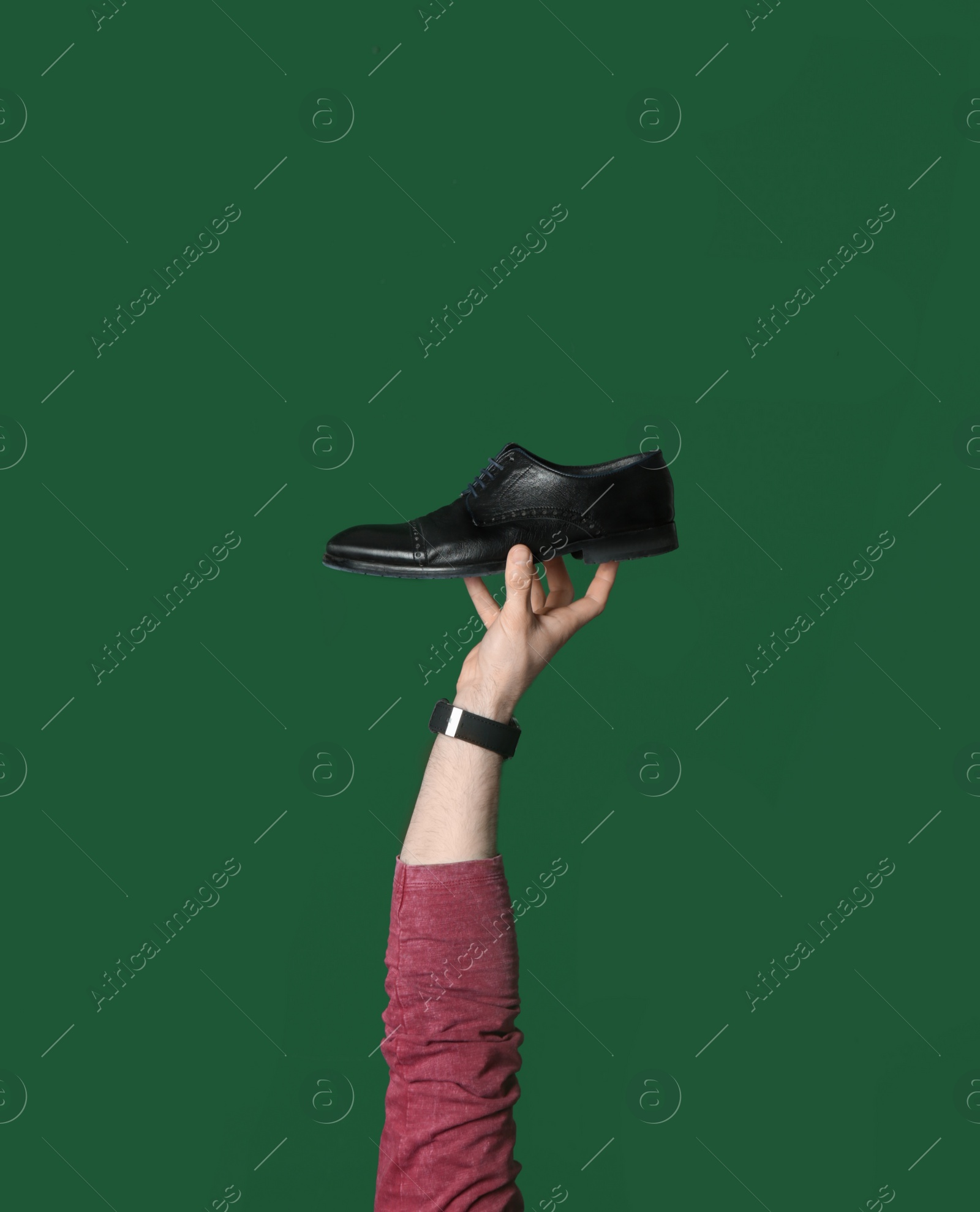 Photo of Man holding stylish shoe on green background, closeup