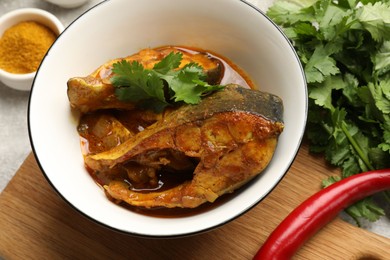 Photo of Tasty fish curry and ingredients on light grey table, closeup. Indian cuisine