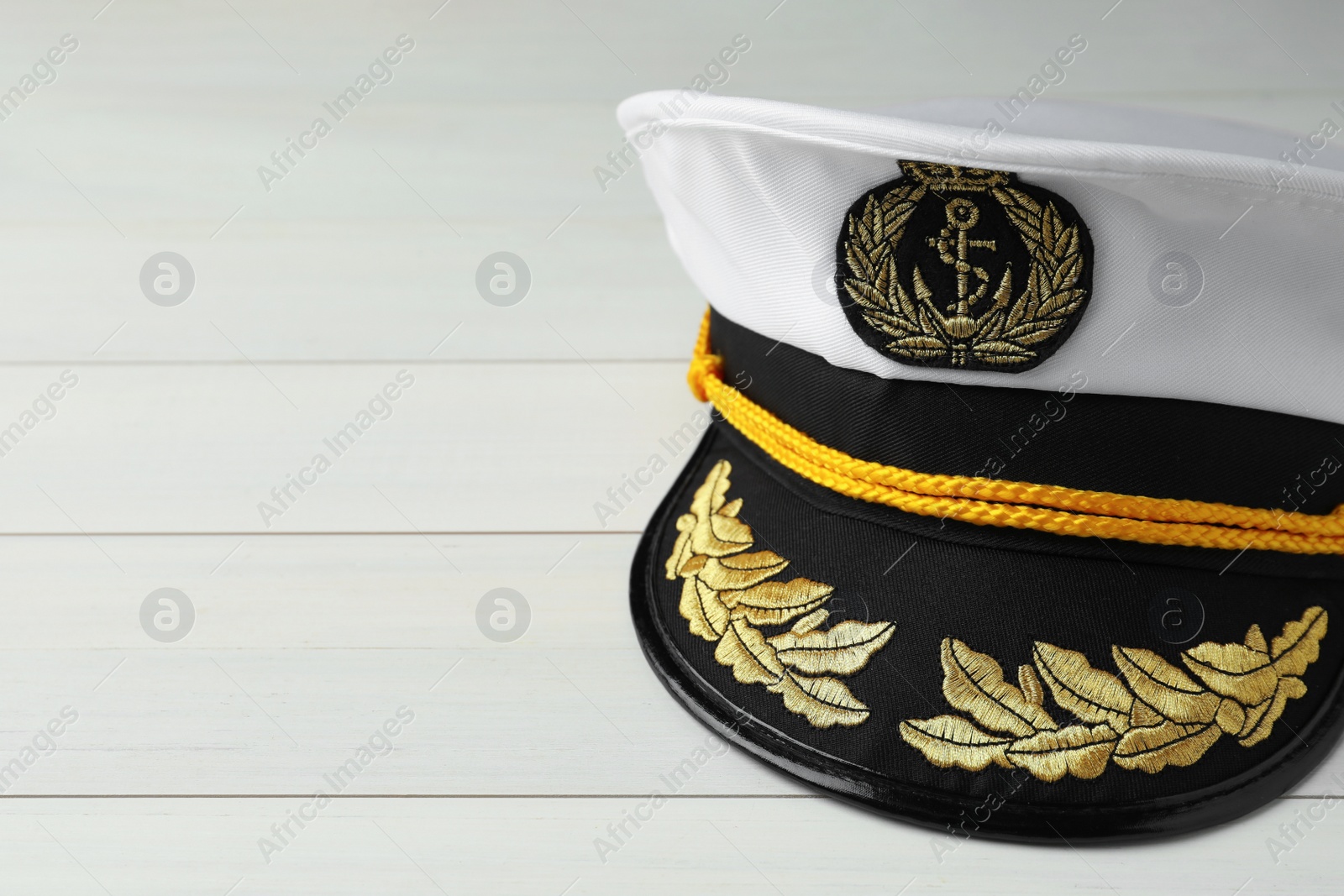 Photo of Peaked cap with accessories on white wooden background, closeup. Space for text