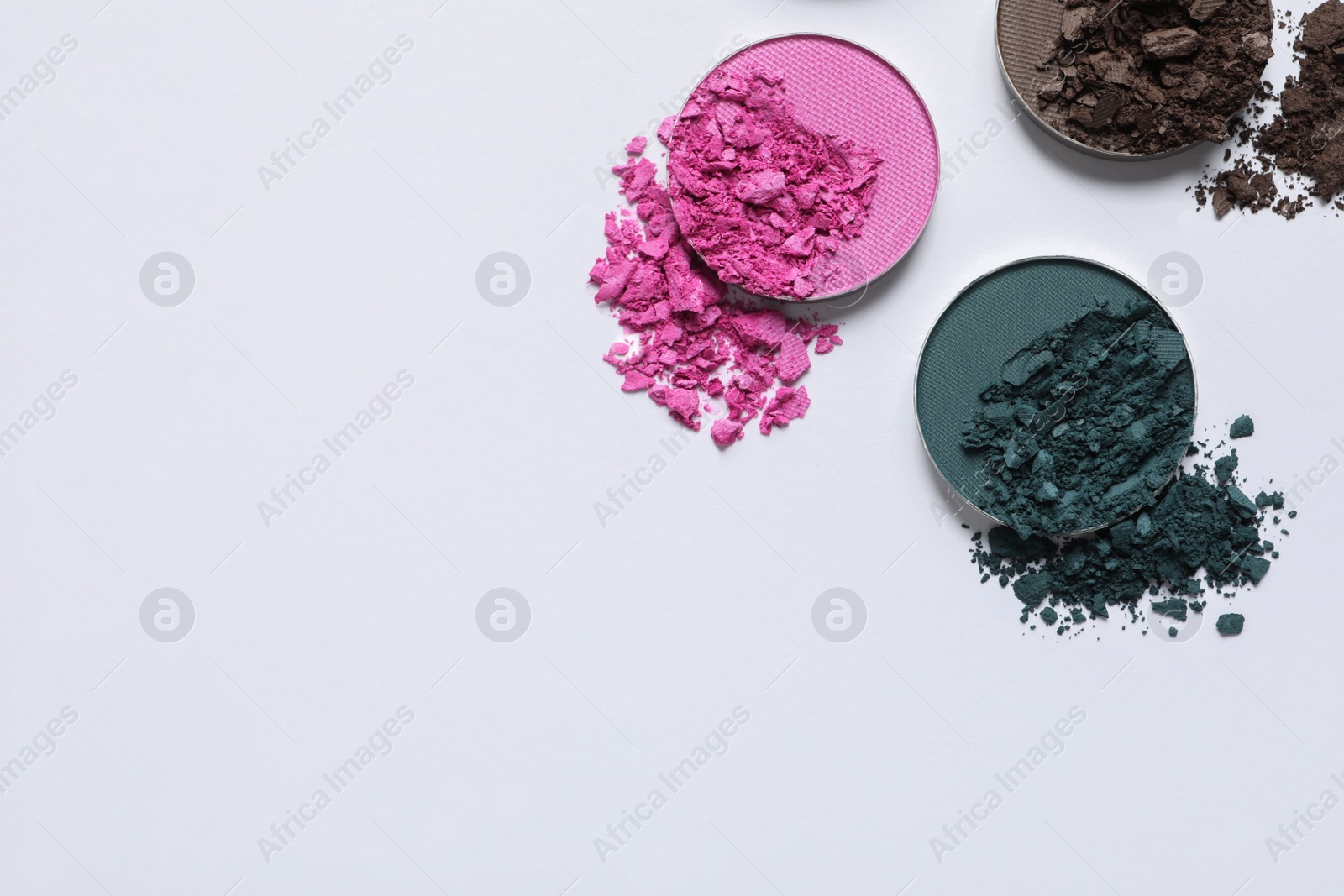 Photo of Different crushed eye shadows on white background, flat lay. Space for text