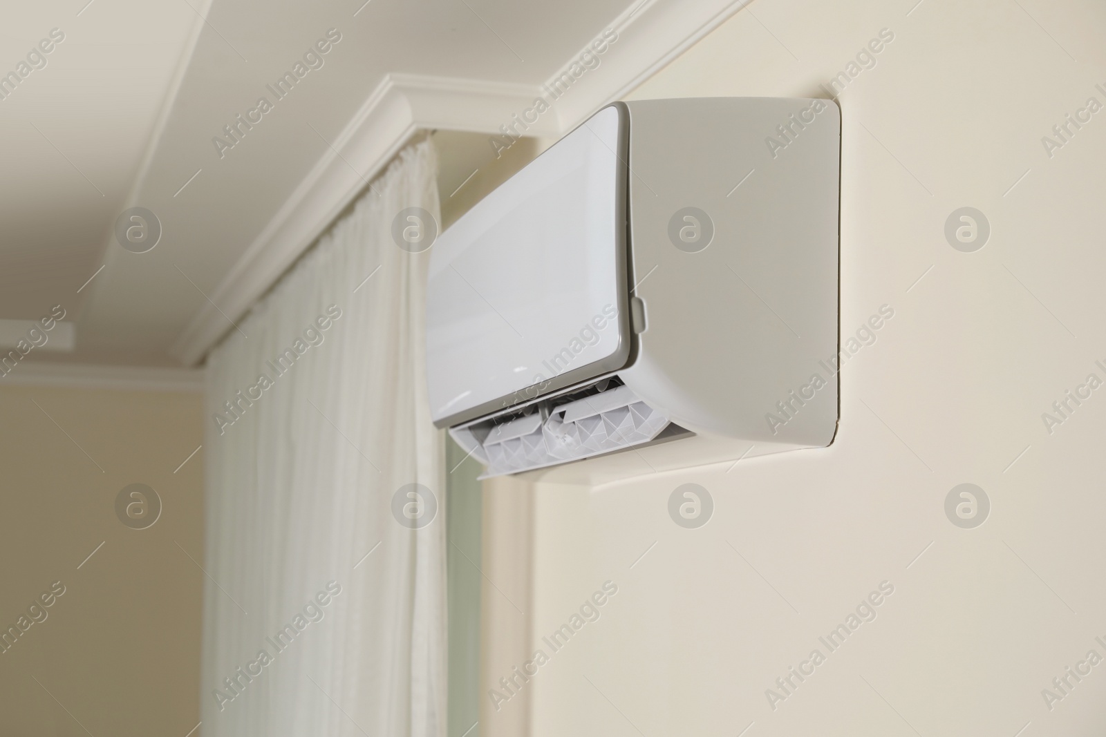 Photo of Modern air conditioner on white wall indoors