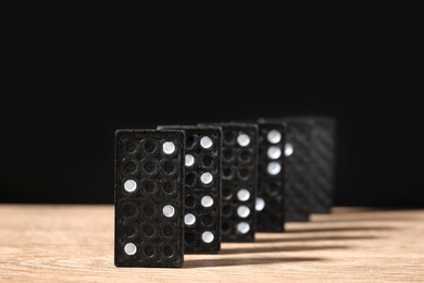Photo of Domino tiles on wooden table against black background