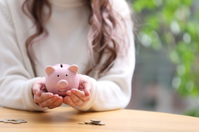 Photo of Woman holding piggy bank at table, closeup