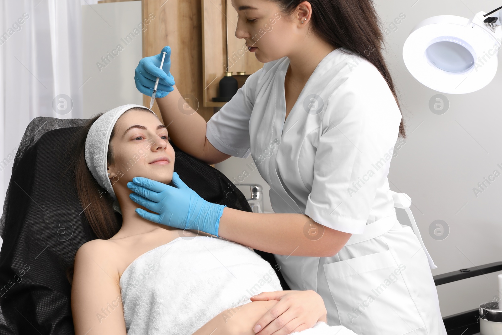 Photo of Cosmetologist giving facial injection to patient in clinic. Cosmetic surgery