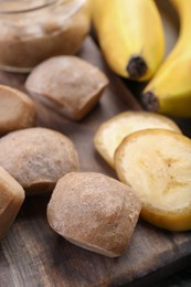 Photo of Frozen banana puree cubes and ingredient on wooden board, closeup