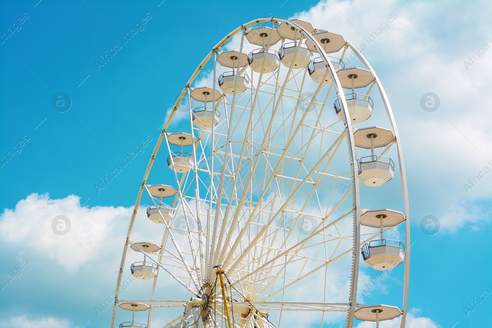 Photo of Large white observation wheel against blue cloudy sky