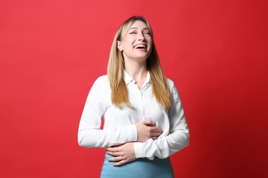 Photo of Beautiful young woman laughing on red background. Funny joke