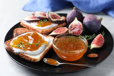 Tasty toasts with fig jam and cream cheese on grey table, closeup