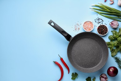 Flat lay composition with frying pan and fresh products on light blue background, space for text