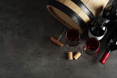 Flat lay composition with glasses and bottles of red wine on stone surface. Space for text