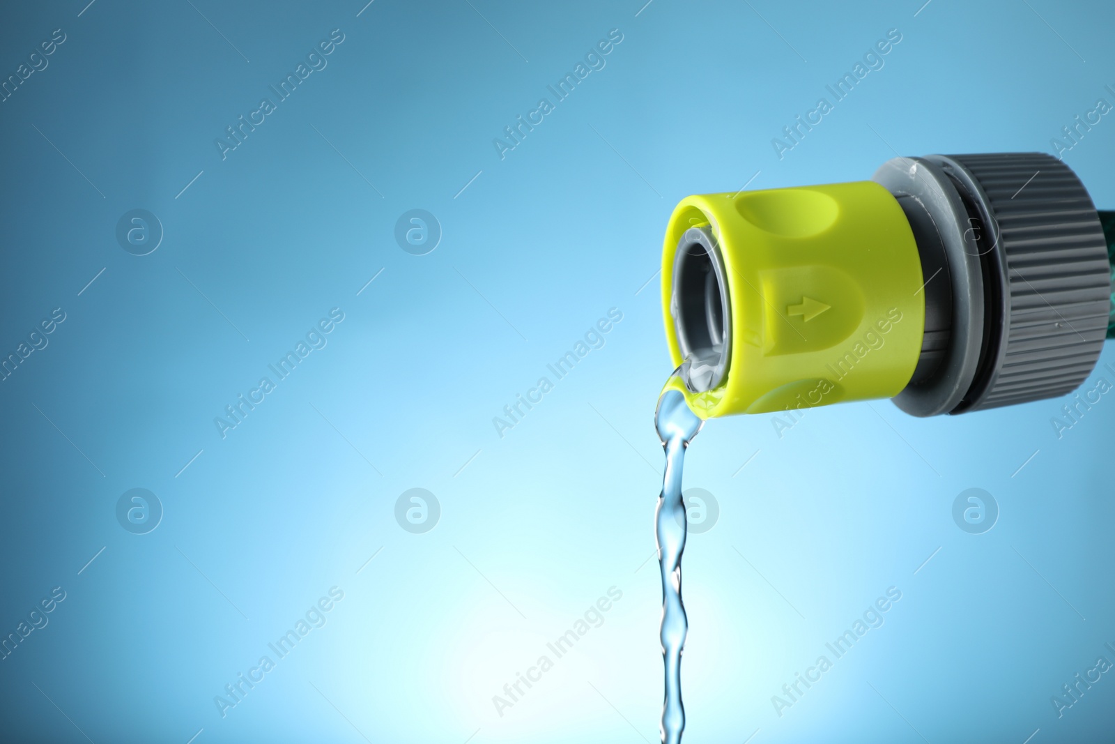 Photo of Water dripping from hose on light blue background, closeup. Space for text