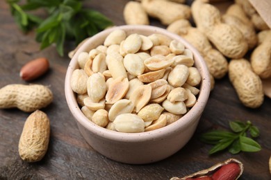 Fresh peanuts and leaves on wooden table, closeup