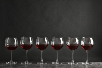 Glasses with red wine on table against dark background