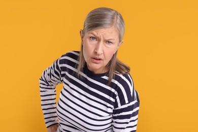 Photo of Portrait of surprised senior woman on yellow background