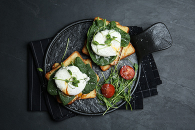 Photo of Delicious poached egg sandwiches served on black table, flat lay