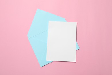 Letter envelope and card on pink background, top view